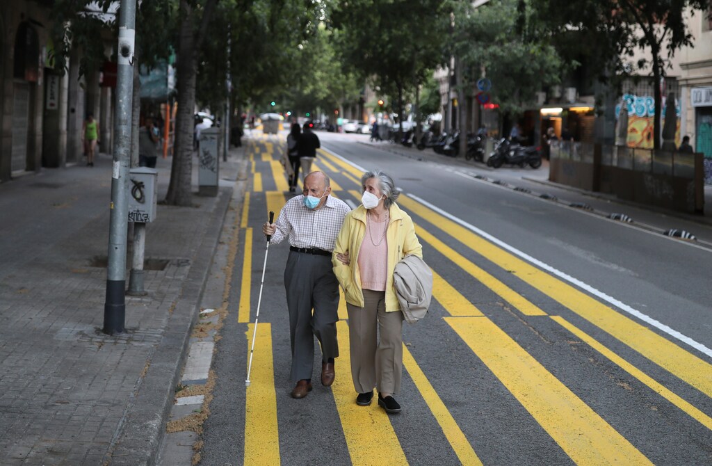 Una pareja de ancianos con máscaras faciales camina por una acera marcada para que los peatones guarden distancia social, durante las horas en que se permite a los ancianos estar al aire libre, mientras continúa la propagación de la enfermedad coronavirus (COVID-19), en Barcelona, España, el 11 de mayo de 2020.
