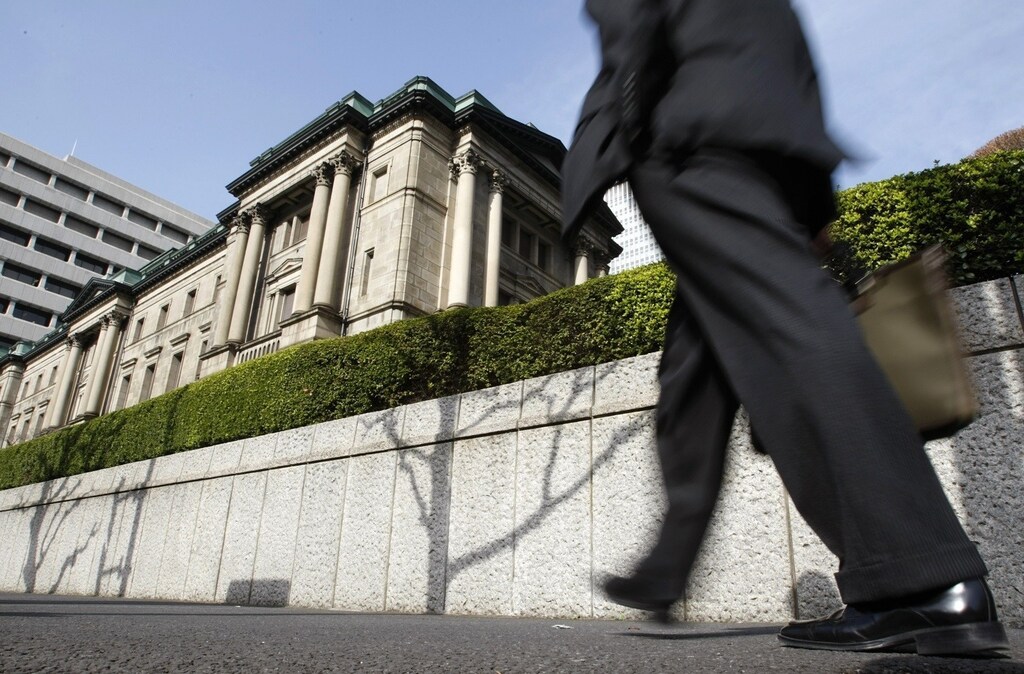A businessman passes by the Bank of Japan building in Tokyo March 18, 2009. Japan's central bank said on Wednesday it would increase the purchase of government bonds by almost a third as the government prepares more spending to help the economy in its worst recession since World War Two.