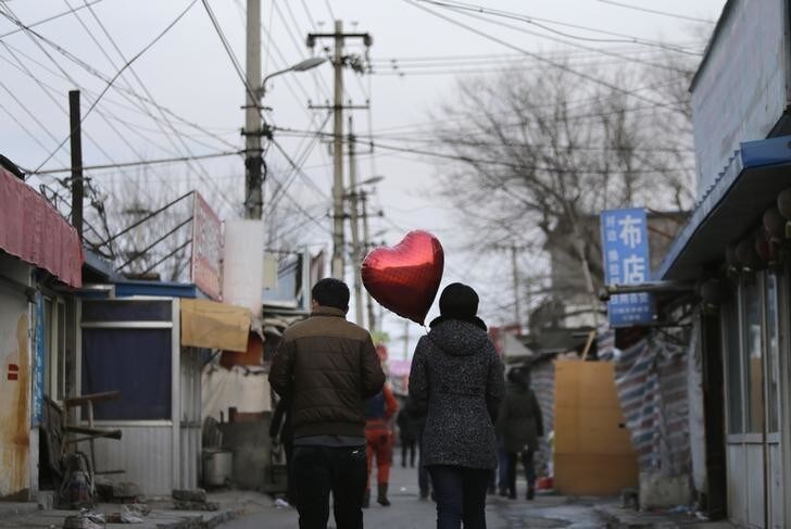 A woman holding a heart-shaped balloon walks with her partner at a residential area for migrant workers on Valentine's Day in Beijing February 14, 2013. REUTERS/Jason Lee (CHINA - Tags: SOCIETY TPX IMAGES OF THE DAY)