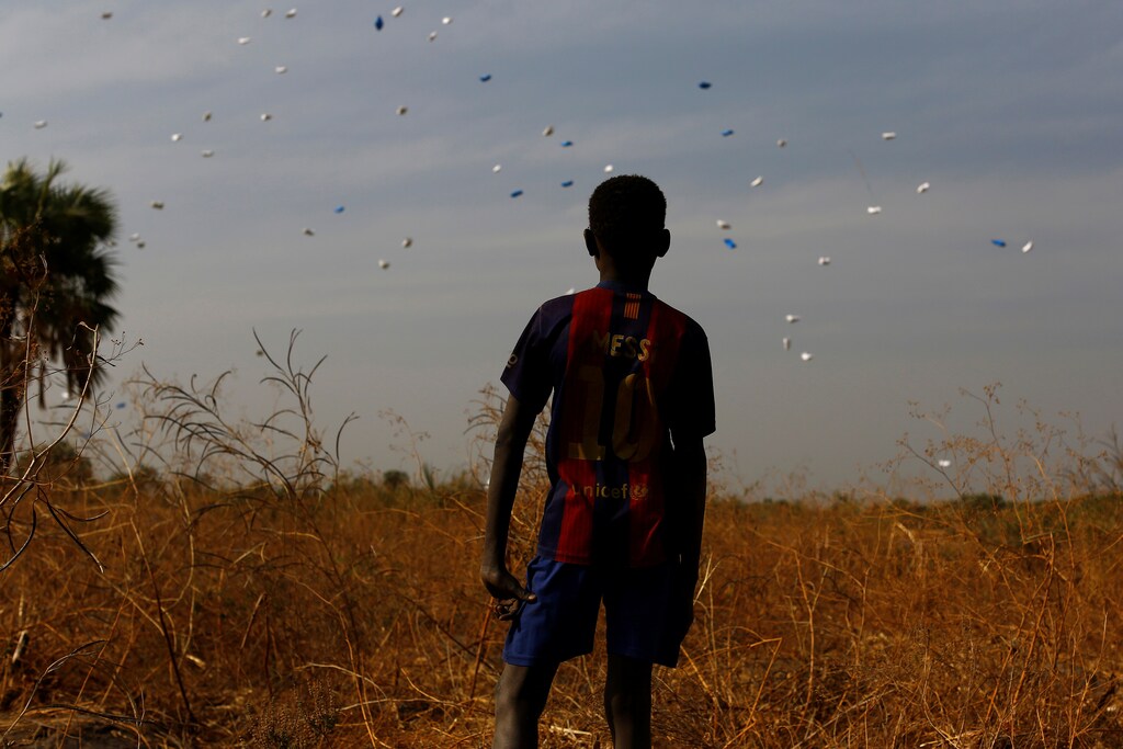 A boy watches sacks of food drop to the ground during a United Nations World Food Programme (WFP) airdrop close to Rubkuai village in Unity State, northern South Sudan, February 18, 2017. Picture taken February 18, 2017. REUTERS/Siegfried Modola - RTSZG0A
