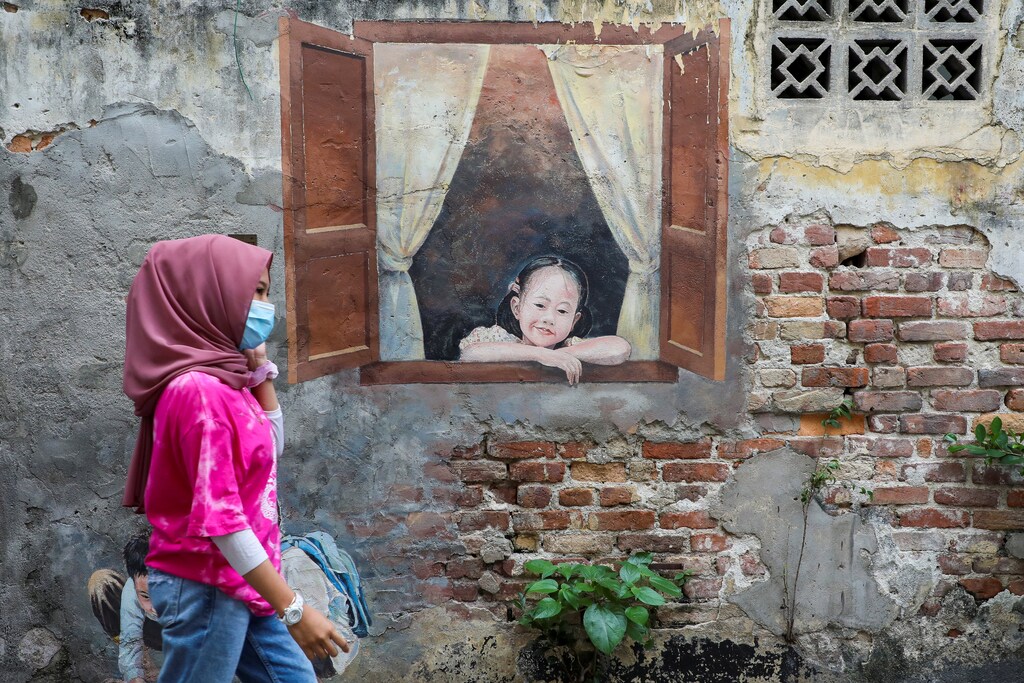 A woman wearing a protective mask walks past a mural, amid the coronavirus disease (COVID-19) outbreak in Kuala Lumpur, Malaysia January 12, 2021. REUTERS/Lim Huey Teng - RC2A6L97PLAR