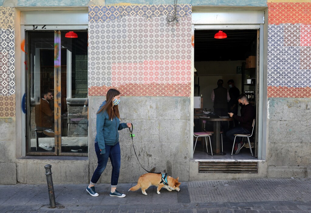 Woman with a dog walks past people inside a bar in central Madrid, Spain October 15, 2020. REUTERS/Sergio Perez - RC21JJ935695