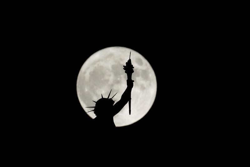 The rising supermoon is seen behind a statue on top of the Natural History Museum in Vienna, Austria November 14, 2016