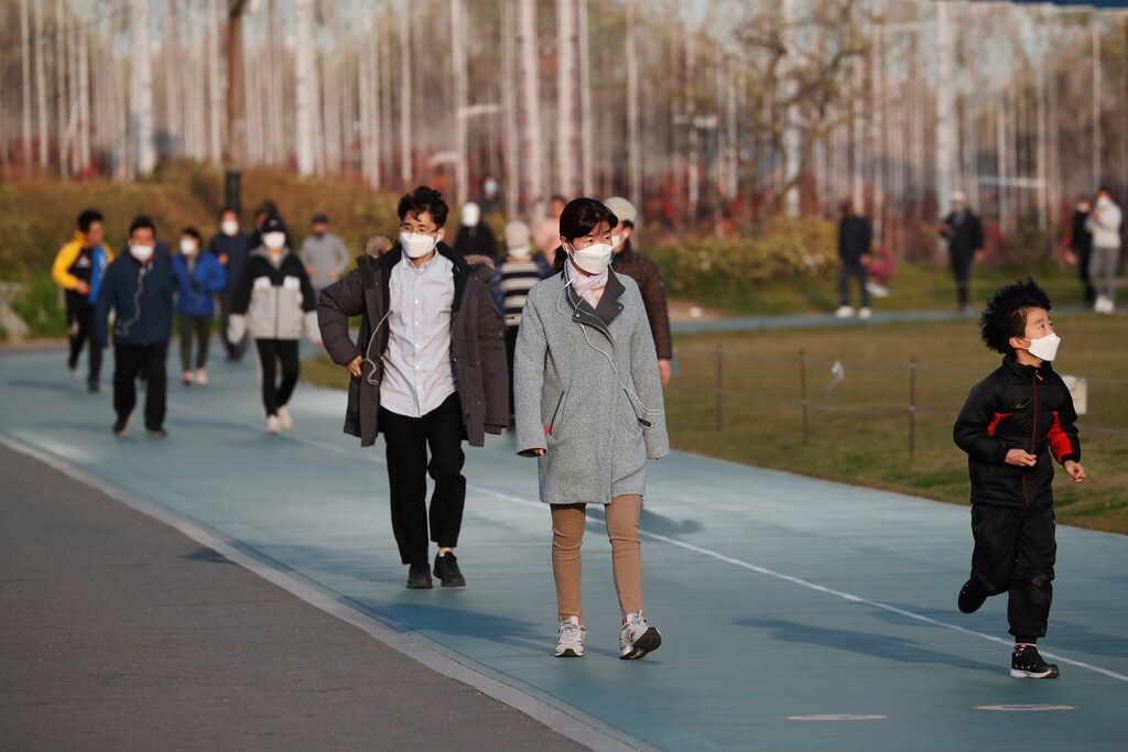 Personas con máscaras para evitar la propagación de la enfermedad coronavirus (COVID-19) caminan por una pista mientras se ejercitan en un parque de Seúl, Corea del Sur, el 24 de abril de 2020.