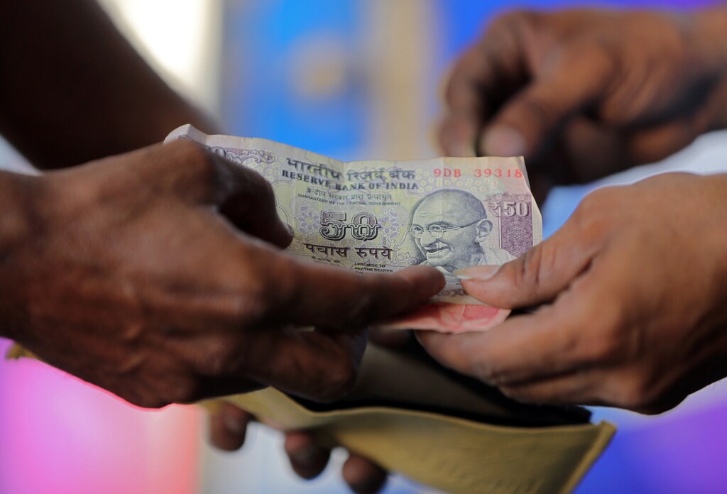 A customer hands a 50-Indian rupee note to an attendant at a fuel station in Ahmedabad, India, October 5, 2018. REUTERS/Amit Dave - RC1DD94DEF00