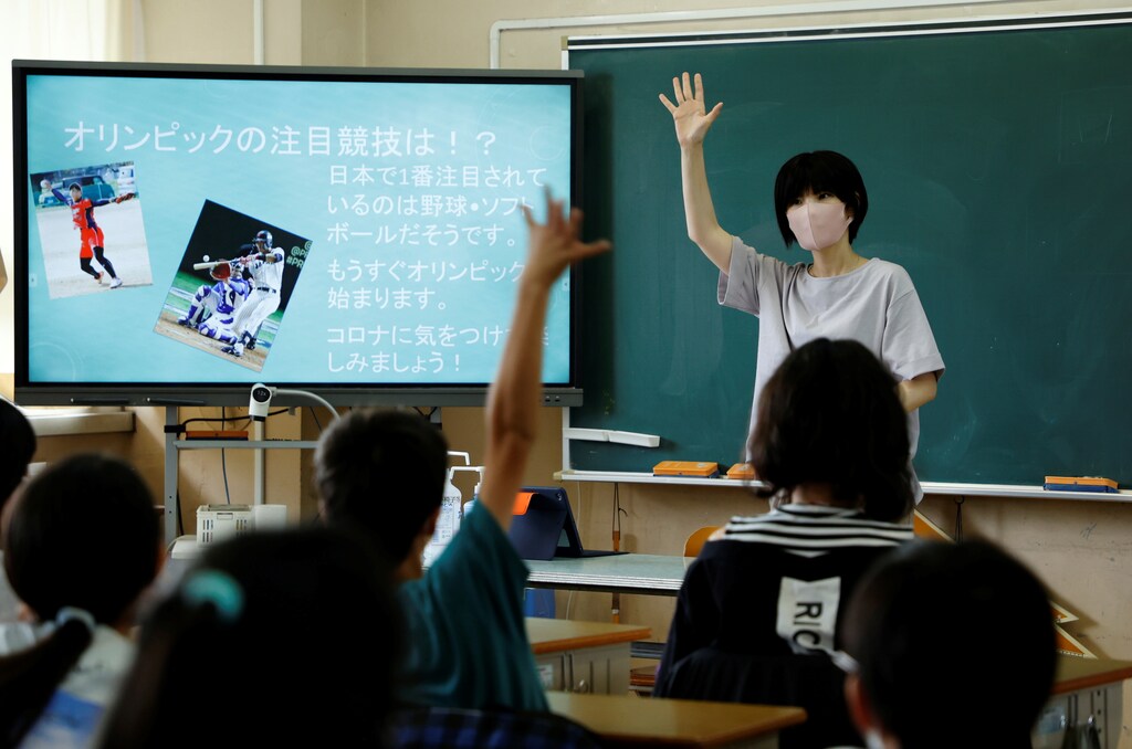A teacher asks students to raise their hands to answer a question about the Olympic Games during class at Shiratori elementary school in Tokyo, Japan, June 30, 2021. Picture taken June 30, 2021. REUTERS/Irene Wang - RC2RAO9AG6DF