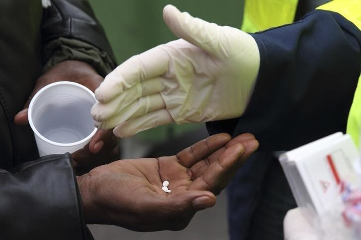 An African migrant receives medicine against scabies from a French doctor during the daily food distribution at the harbour in Calais, northern France, May 27, 2014. French sanitary authorities distribute medicine against the disease and announced that they will close three such camps tomorrow morning where several hundred illegal migrants gather before attempting to cross the channel to Britain. REUTERS/Pascal Rossignol (FRANCE - Tags: SOCIETY POVERTY IMMIGRATION HEALTH)