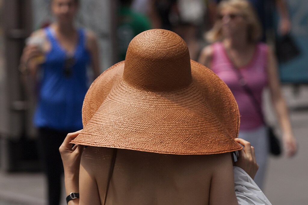 A woman covers herself with a large hat in Times Square during a heat wave in Manhattan, New York, July 19, 2013.