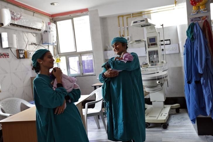 Rekha Patel, 42 (R), from Britain, holds her week-old-baby girl Gabriella, as she stands next to a doctor at the Akanksha IVF centre in Anand town, about 70 km (44 miles) south of the western Indian city of Ahmedabad August 25, 2013. Gabriella was carried and delivered by an Indian surrogate mother Naina Patel. India is a leading centre for surrogate motherhood, partly due to Hinduism's acceptance of the concept. The world's second test tube baby was born in Kolkata only two months after Louise Brown in 1978. Rising demand from abroad for Indian surrogate mothers has turned "surrogacy tourism" there into a billion dollar industry, according to a report by the Law Commission of India. Picture taken August 25, 2013. REUTERS/Mansi Thapliyal