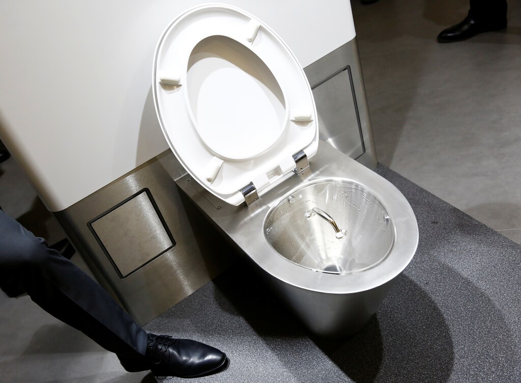 A man stands next to a toilet design by Helbling at the Reinvented Toilet Expo showcasing sewerless sanitation technology in Beijing, China November 6, 2018. REUTERS/Thomas Peter - RC1C69F0E630