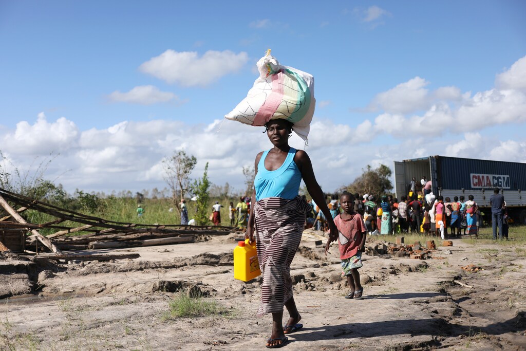 A Women walks after receiving parcel from an aid organisation after Cyclone Idai, near Dondo village outside Beira, Mozambique, March 24, 2019. REUTERS/Siphiwe Sibeko - RC136D4D9B70