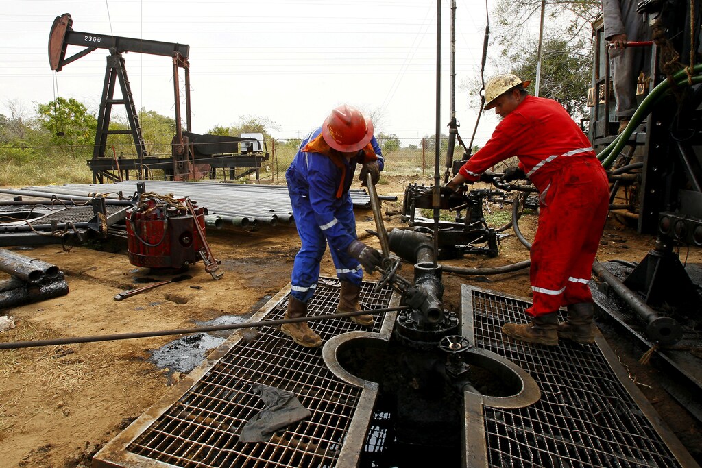 Men work at an oil pump in Lagunillas, Ciudad Ojeda, in the state of Zulia, Venezuela, March 18, 2015. REUTERS/Isaac Urrutia/File Photo - S1AETHOJITAA