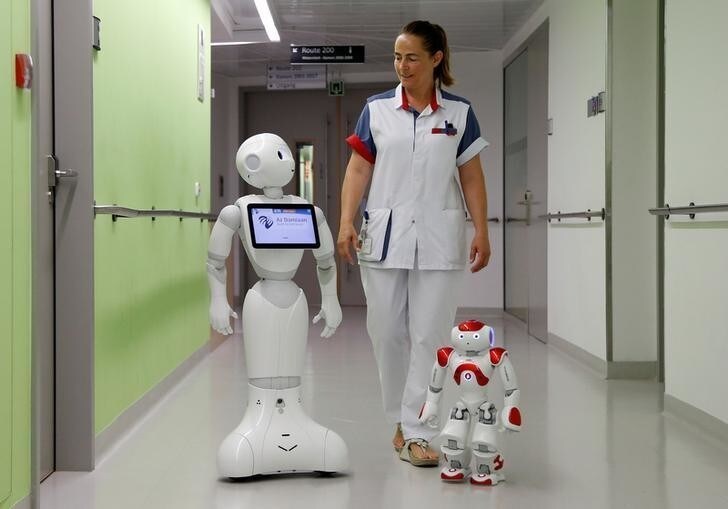 A nurse walks with "Pepper" (L) and "Zora" the robots, humanoid robots designed to welcome and take care of visitors and patients, at AZ Damiaan hospital in Ostend, Belgium June 16, 2016. REUTERS/Francois Lenoir