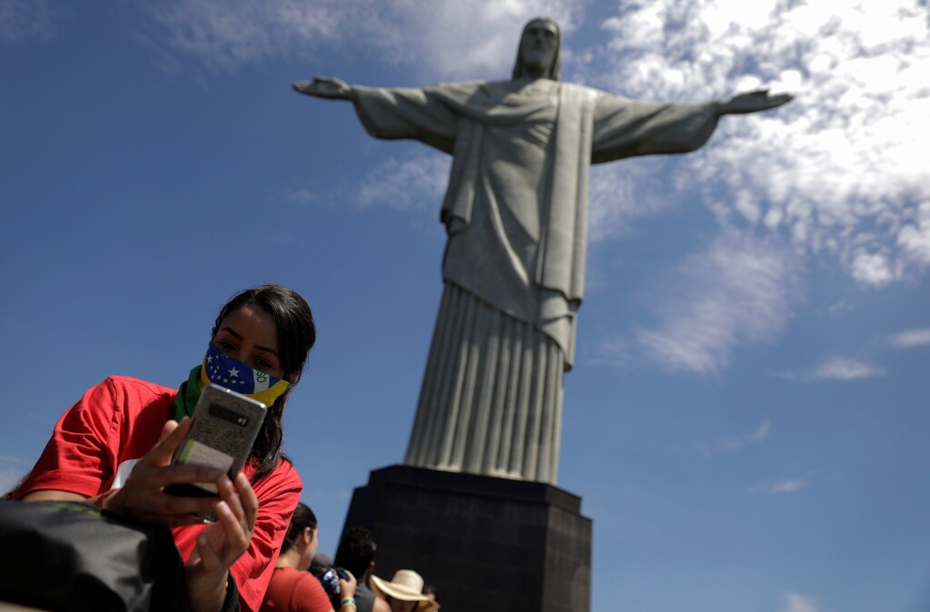 A tourist takes a selfie as she uses a Brazilian flag as a protective face mask, during a visit to Christ the Redeemer statue after reports of coronavirus in Rio de Janeiro, Brazil, March 16, 2020. REUTERS/Ricardo Moraes - RC27LF95AVY7
