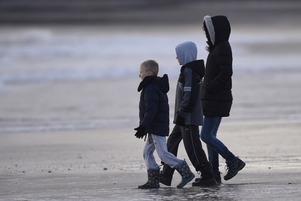 Children watch the waves during stormy conditions at Tenby, South Wales, December 24, 2015. REUTERS/Rebecca Naden - RTX1ZZO7