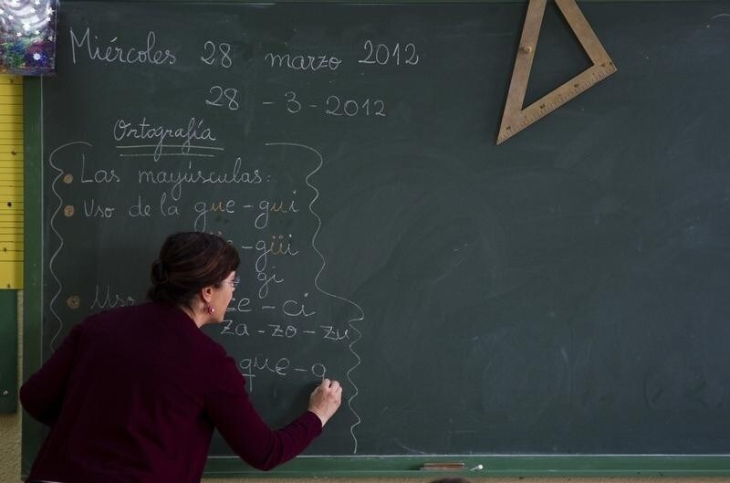 A teacher writes on a blackboard during class at a public school in Madrid, March 28, 2012. Spain will announce some of its deepest budget cuts ever on Friday, though evaporating growth prospects mean it is likely to fall short of what is needed to meet strict public deficit targets. Cuts in public education have sparked nationwide protests and more cuts are likely to be handed down by autonomous regions after the newly installed conservative central government presents its 2012 budget on Friday. REUTERS/Sergio Perez (SPAIN - Tags: EDUCATION BUSINESS SOCIETY POLITICS) - RTR3005W
