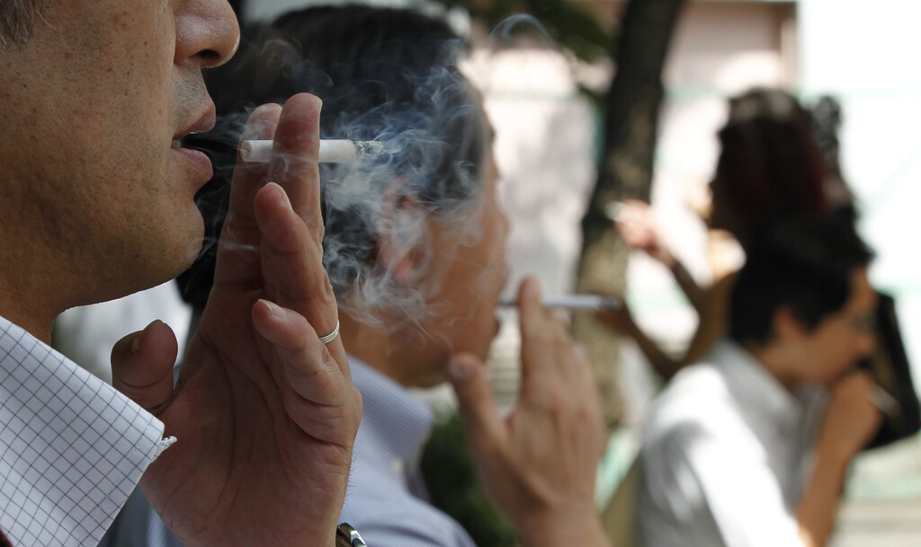 People smoke cigarettes at a smoking area in Tokyo September 16, 2011. REUTERS/Toru Hanai (JAPAN - Tags: BUSINESS POLITICS HEALTH) - GM1E79G13DF01