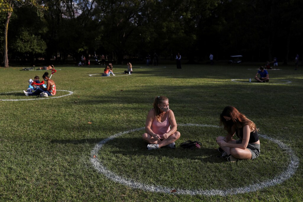 Women sit in a field where circles were painted to help visitors maintain social distancing at Ibirapuera Park after it was reopened as the city eases the restrictions imposed to control the spread of the coronavirus disease (COVID-19), in Sao Paulo, Brazil July 13, 2020