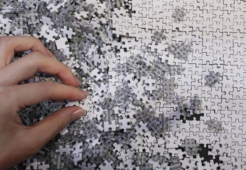 An employee of puzzle maker Beverly holds a piece of the company's white micro 1000 piece jigsaw puzzle at the International Toy Show in Tokyo June 14, 2012. The four-day event will open to public on Saturday, showcasing a total of about 35,000 products by 144 toy manufacturers.