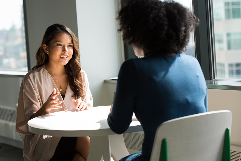 Two women at work talking in a meeting.