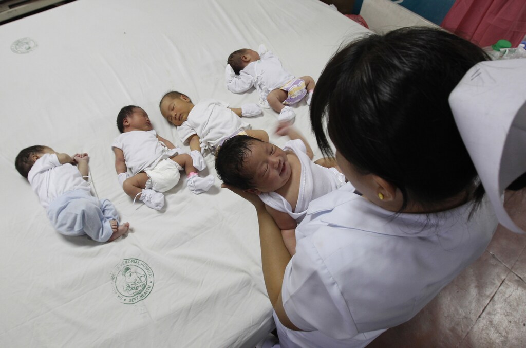 A nurse carries a newly-born baby inside a nursery ward of Jose Fabella memorial hospital in Manila August 3, 2012. Manila's Roman Catholic bishops will be holding a protest on Saturday against the approval of the Reproductive Health Bill (RH Bill) which is still being debated in the lower house of Congress. REUTERS/Romeo Ranoco (PHILIPPINES - Tags: POLITICS SOCIETY HEALTH RELIGION) - RTR35ZKC