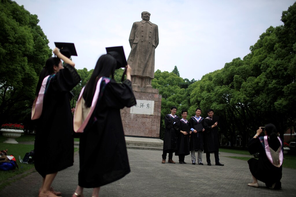 Graduates throw their mortar boards as they pose for pictures at Fudan University in Shanghai, China May 31, 2016.