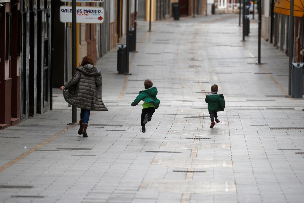 A woman and two children run along the empty La Bola street, after restrictions were partially lifted for children for the first time in six weeks, during the coronavirus disease (COVID-19) outbreak in Ronda, Spain, April 26, 2020. REUTERS/Jon Nazca - RC2ECG915UQL