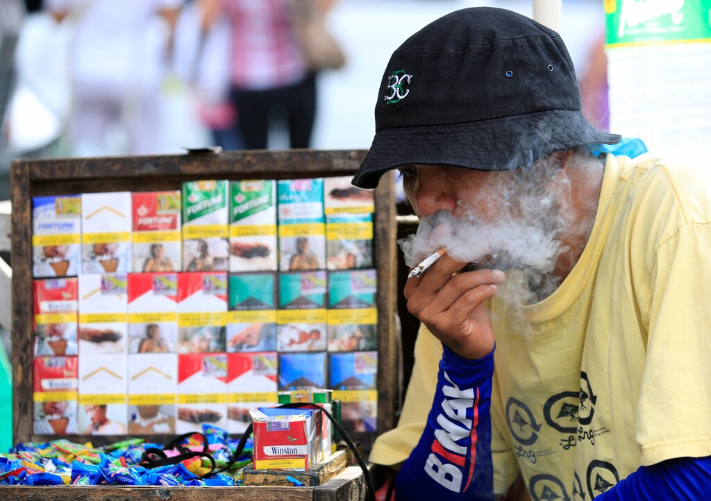 A vendor smokes beside his cigarette stall, while waiting along a main street, in metro Manila, Philippines May 19, 2017. REUTERS/Romeo Ranoco - RC1D5C8E8790