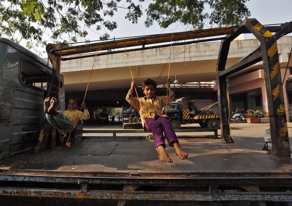 Children play on improvised swings on a tow truck parked on a roadside in Mumbai March 24, 2014. REUTERS/Mansi Thapliyal (INDIA - Tags: SOCIETY) - RTR3IBMP