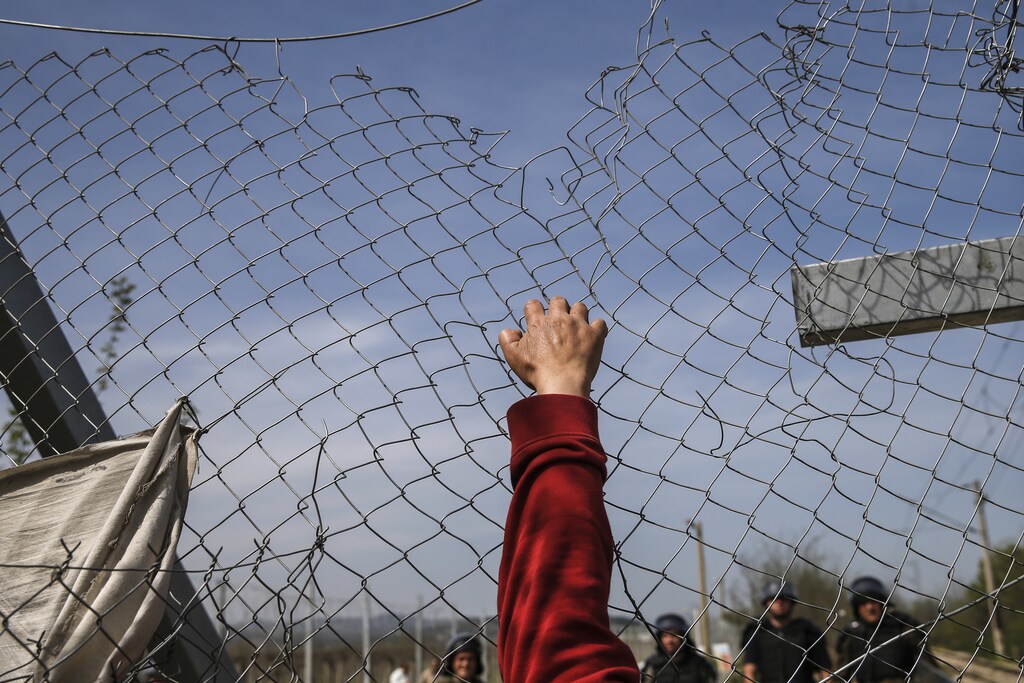 A migrant tries to open a border fence after migrants and refugees tried to open it at a makeshift camp at the Greek-Macedonian border near the village of Idomeni, Greece, April 7, 2016