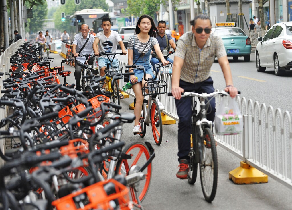 People ride past shared bikes at a bike lane in Wuhan, Hubei province, China June 26, 2017. Picture taken June 26, 2017. REUTERS/Stringer ATTENTION EDITORS - THIS IMAGE WAS PROVIDED BY A THIRD PARTY. CHINA OUT. NO COMMERCIAL OR EDITORIAL SALES IN CHINA. - RC1774332AA0