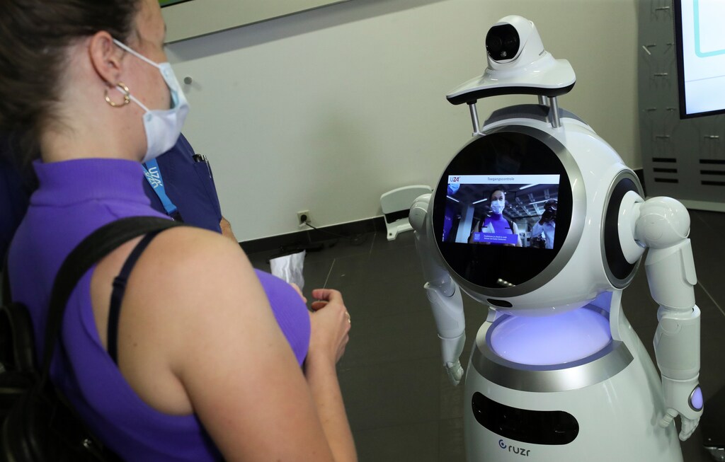 Un visitante del Hospital Universitario de Amberes (UZA) interactúa con un robot llamado CRUZR, puesto a disposición de los hospitales y otros lugares por la empresa belga ZoraBots para controlar la temperatura y el buen posicionamiento de la máscara facial protectora, en medio del brote de la enfermedad coronavirus (COVID-19), en Amberes, Bélgica, el 29 de mayo de 2020.