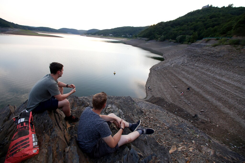 Young men relax at the bank of the Edersee reservoir with low water level near Waldeck, Germany July 21, 2017. Picture taken July 21, 2017. REUTERS/Ralph Orlowski - RC17FA9443E0
