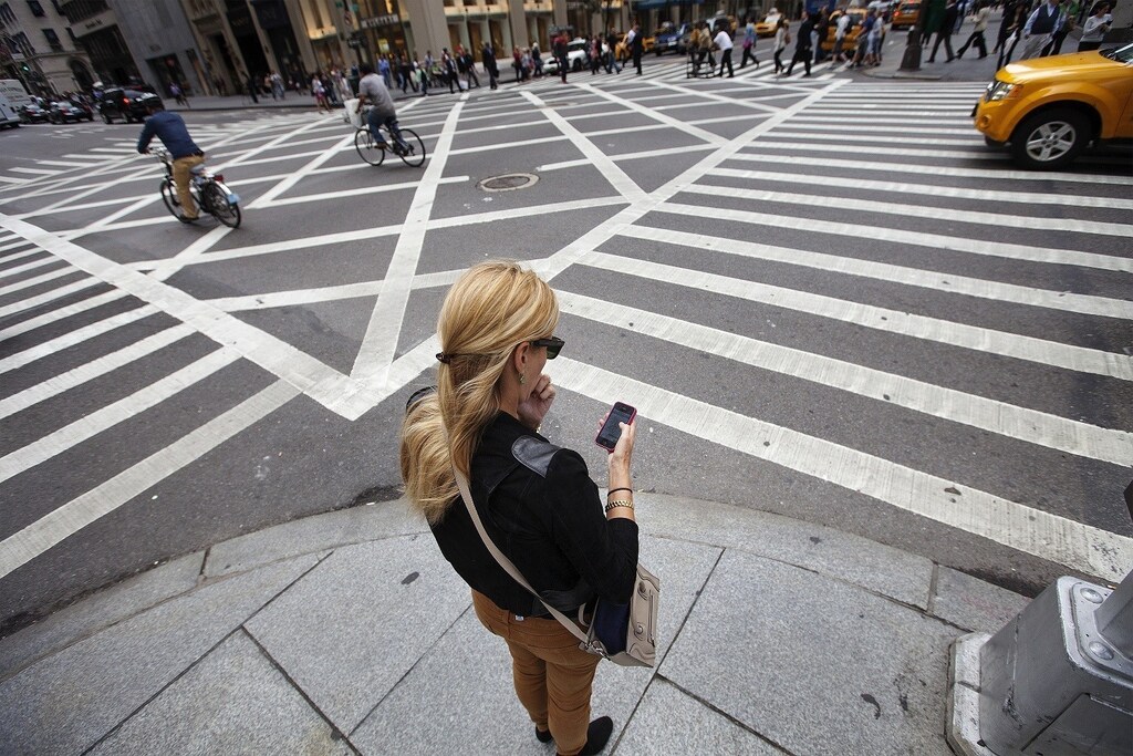 A woman uses her Apple iPhone while waiting to cross 5th Avenue in New York, September 20, 2012. Apple's iPhone 5 goes on sale tomorrow as Apple works to increase it's market share in the mobile phone market. REUTERS/Lucas Jackson (UNITED STATES - Tags: BUSINESS SCIENCE TECHNOLOGY TELECOMS SOCIETY) - RTR387LK