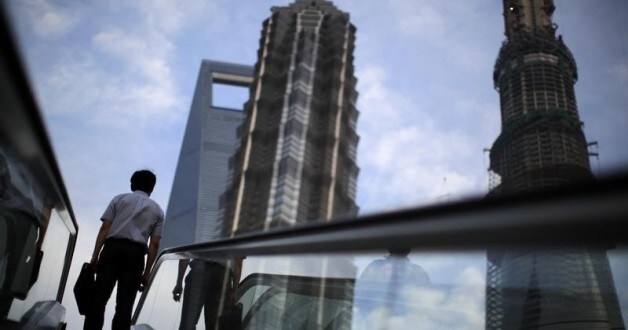 A man rides an escalator near Shanghai Tower.