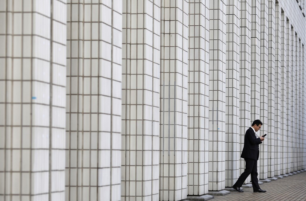 A man walks out from a business building in Tokyo January 24, 2013. Sentiment among Japanese manufacturers improved for a second straight month and is expected to turn into a positive reading in the coming few months, a Reuters poll showed, providing some evidence that the economy is crawling out of a mild recession. REUTERS/Toru Hanai (JAPAN - Tags: BUSINESS TPX IMAGES OF THE DAY) - GM1E91O14AX01