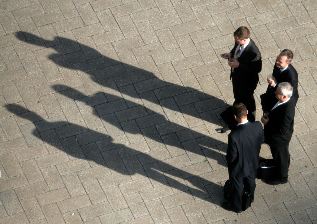 Businessmen cast shadows they stop to watch final day of fifth Ashes test between England and Australia in London. Businessmen cast shadows in the afternoon sun as they stop to watch the final day of the fifth Ashes test match between England and Australia on a giant outdoor TV screen in London's Canary Wharf financial district September 12, 2005. England won the Ashes for the first time since 1987 after the fifth and final test against Australia ended in a draw on Monday, giving the hosts a 2-1 victory in the series. REUTERS/Kevin Coombs - RTR10LJ6