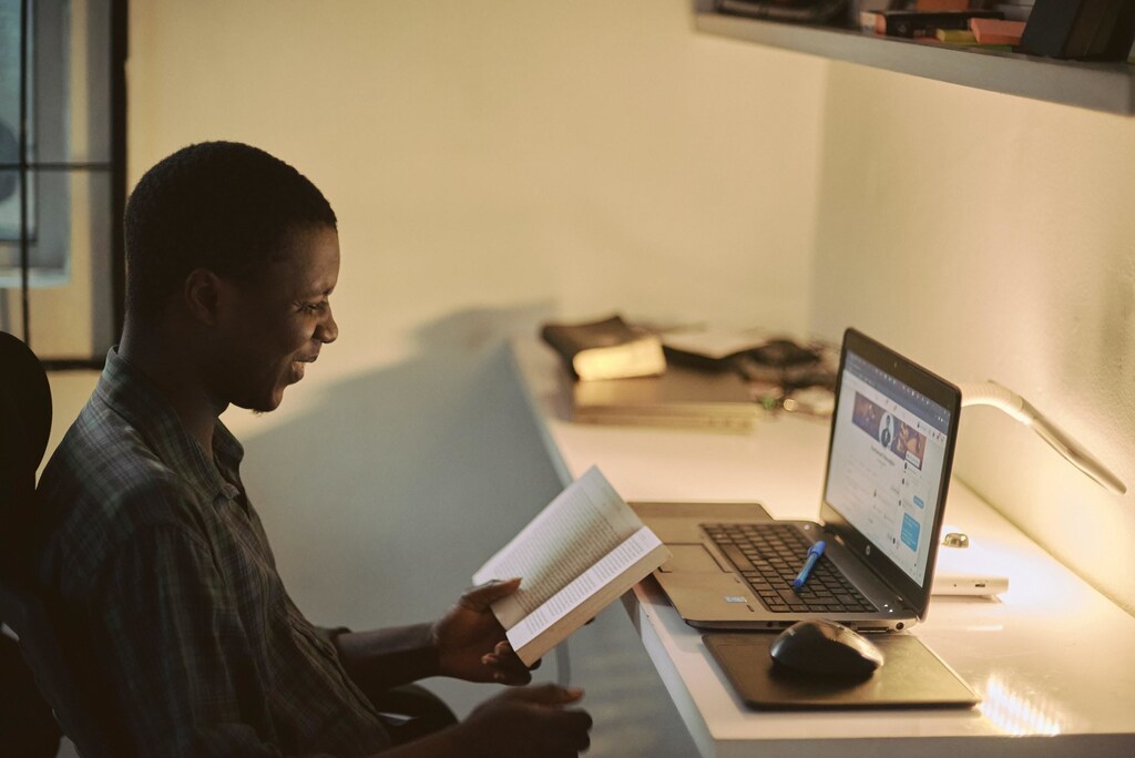 Online learning could be used to revolutionize education for the good. Pictured here: Student at laptop holding a book.