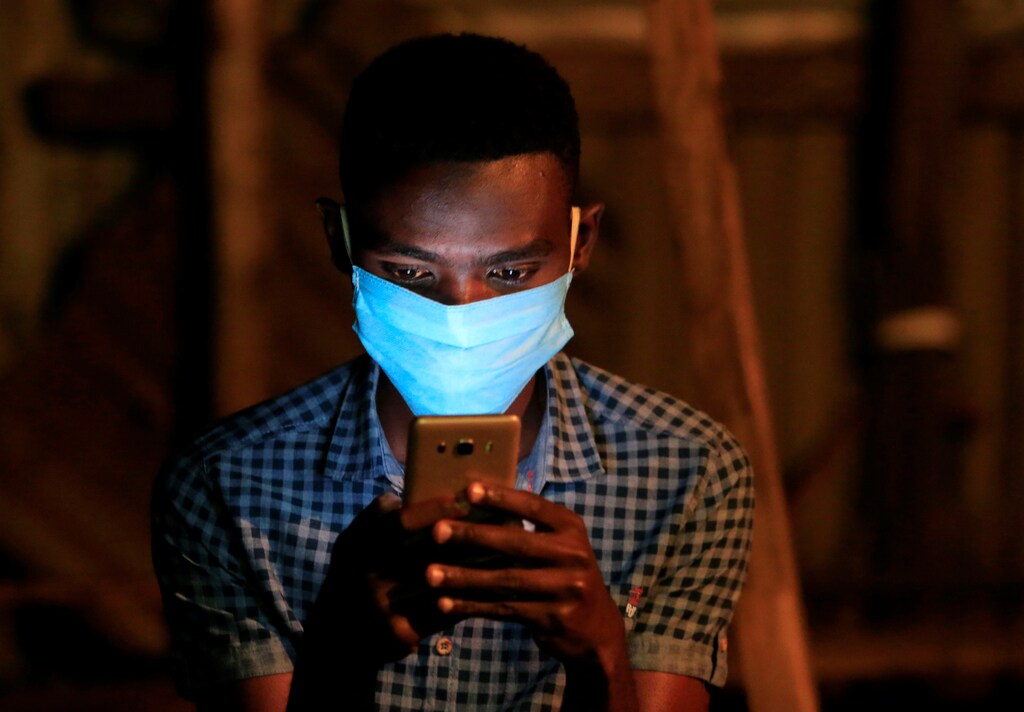 A soccer fan uses his mobile phone for betting during a television broadcast at a soccer theatre called the San Siro Stadium as the English Premier League season resumes after a three-month stoppage due to the coronavirus disease (COVID-19) spread, in Kibera district of Nairobi, Kenya June 17, 2020.
