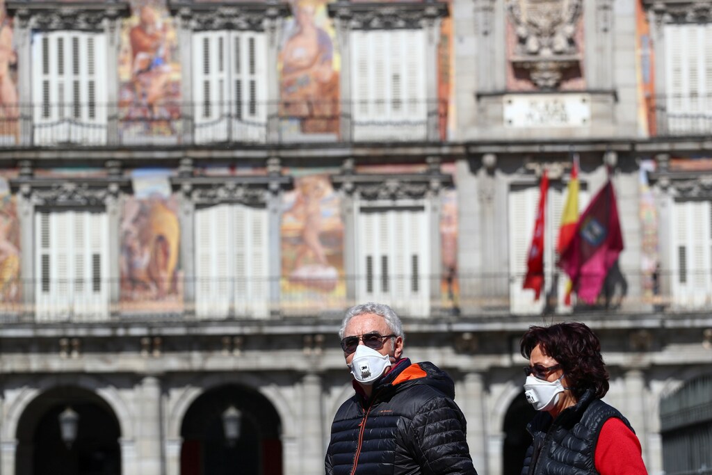 Una pareja lleva máscaras protectoras mientras caminan por uno de los principales monumentos turísticos de la Plaza Mayor de Madrid, España, el 9 de marzo de 2020.