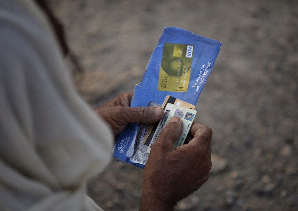 A man, fleeing a military offensive in South Waziristan, holds his national identity card and an ATM cash card while waiting to get food handouts at a distribution point for internally displaced persons (IDPs) in Dera Ismail Khan, in Pakistan's restive North West Frontier Province, October 27, 2009. Pakistan forces killed 19 militants in an intense clash in South Waziristan on Monday while insurgents aiming to divert the army's attention launched a raid in another northwestern region, officials said. REUTERS/Faisal Mahmood (PAKISTAN CONFLICT) - GM1E5AR1D8001