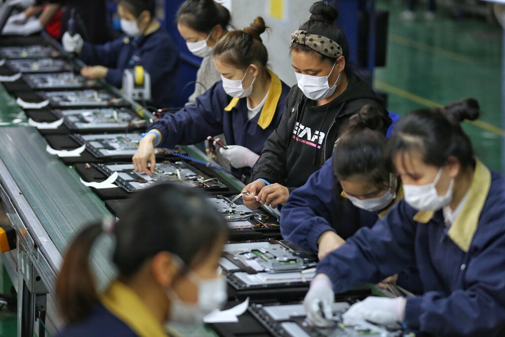 Employees, wearing masks, work on a production line manufacturing display monitors at a TPV factory in Wuhan, Hubei province, the epicentre of the novel coronavirus disease (COVID-19) outbreak in China, April 7, 2020. China Daily via REUTERS ATTENTION EDITORS - THIS IMAGE WAS PROVIDED BY A THIRD PARTY. CHINA OUT. - RC2LZF9Q7S68