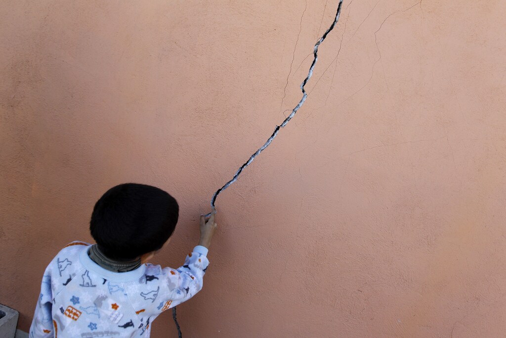 A kid touches a crack on a wall at his damaged home in the community of Oaxaca, on the outskirts of Mexicali April 7, 2010. Scared families south of the Mexico-California border readied to sleep outside for a second night on Monday after a big earthquake tore cracks in roads and houses and dozens of aftershocks rattled the area. REUTERS/Tomas Bravo (MEXICO - Tags: DISASTER) - GM1E6480BDO01