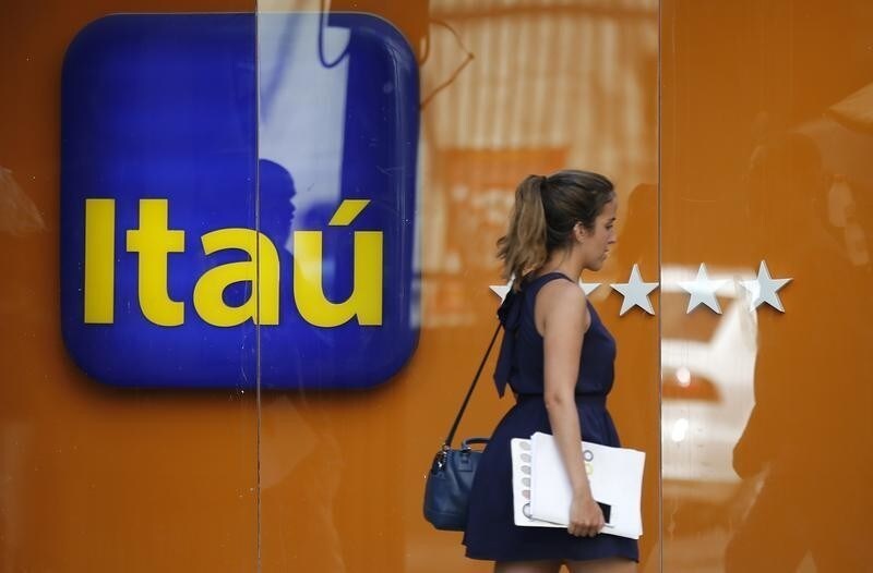 A woman walks past an Itau branch office in Rio de Janeiro January 29, 2014. Brazilian bank Itau Unibanco Holding SA said it would acquire control of leading Chilean bank CorpBanca SA, a deal worth an estimated $3.7 billion that would help it expand beyond its stagnant home turf into more dynamic markets. REUTERS/Sergio Moraes (BRAZIL - Tags: BUSINESS) - GM1EA1U05J601