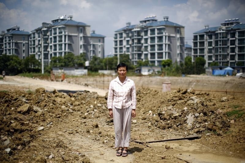 Xu Haifeng poses at a construction site area where her house stood in Wuxi, Jiangsu province, August 20, 2013. When Xu's home was razed three years ago, she went to China's capital Beijing to complain about the city and county governments that ordered the demolition. Since then she says family members have been kidnapped at least 18 times, typically having black bags thrust over their heads before being taken to a hotel-turned-illegal jail in the eastern city of Wuxi and locked for weeks in a tiny, windowless room. Xu's story is shocking even in a country that has become used to tales of arbitrary and sometimes violent land expropriations. It illustrates how the stresses from the deep indebtedness of China's local governments extend beyond banks into the lives of ordinary Chinese, as hard-up authorities resort to any means they can in a desperate scramble for funds. Picture taken August 20, 2013. REUTERS/Carlos Barria (CHINA - Tags: BUSINESS CONSTRUCTION POLITICS LAW) - GM1E9930ESR01