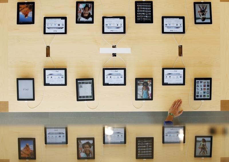An employee rests a hand on a table displaying iPads as part of the display is reflected on a glass surface at the Passeig de Gracia Apple store in Barcelona July 26, 2012. The store will become Apple's largest store in southern Europe when it opens officially on July 28. REUTERS/Albert Gea (SPAIN - Tags: BUSINESS TELECOMS) - GM1E87R04WV01