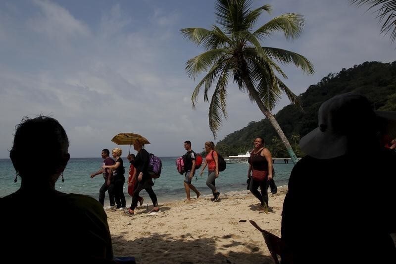 Tourists look at Cuban migrants arriving to the beach safely after crossing the border from Colombia through the jungle into La Miel, in the province of Guna Yala, Panama December 2, 2015. According to local authorities in La Miel, some 100 to 150 Cubans have been entering Panama from Colombia every day for the last three months. Scores of Cubans have come to Panama as they seek overland passage towards the United States fearing a recent detente between Washington and Havana could end their preferential treatment. REUTERS/Carlos Jasso - GF20000082833