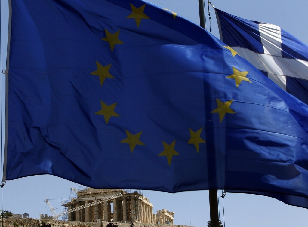 A European Union (E.U.) flag (front) and a Greek flag flutter in front of the monument of Parthenon on Acropolis hill in Athens June 17, 2012. Greeks voted on Sunday in an election that could decide whether their heavily indebted country stays in the euro zone or heads for the exit, potentially unleashing shocks that could break up the single currency. REUTERS/John Kolesidis (GREECE - Tags: POLITICS BUSINESS ELECTIONS) - RTR33RAB