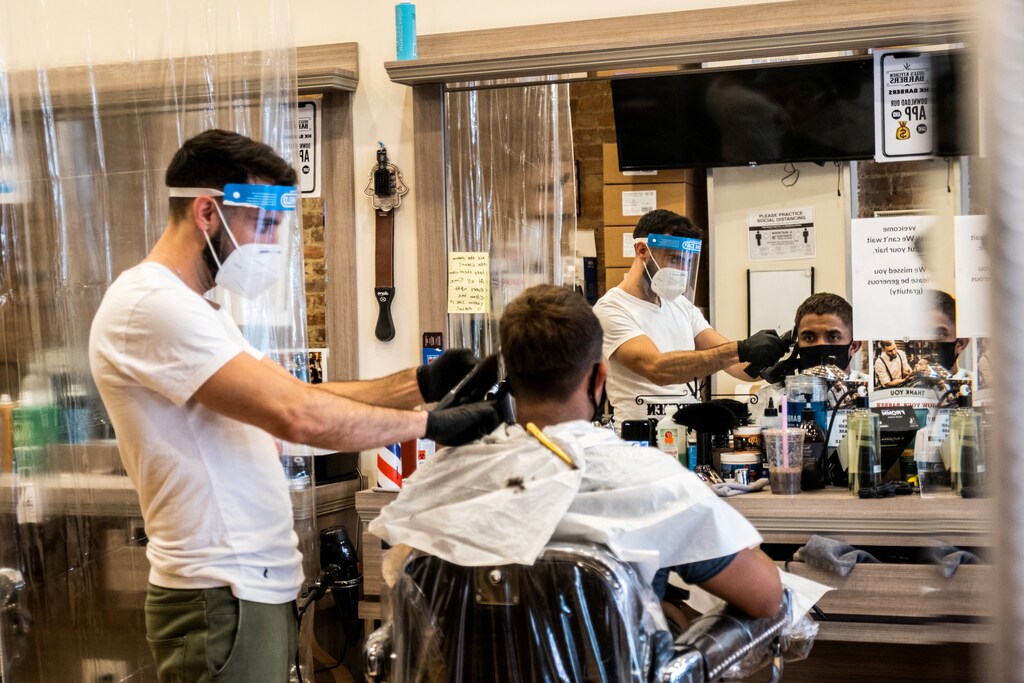 A customer wearing a face mask gets his hair cut at a barber shop after its reopening following the outbreak of the coronavirus disease (COVID-19), in New York City, New York, U.S., July 5, 2020. REUTERS/Jeenah Moon TPX IMAGES OF THE DAY - RC2BNH9HQKQ7