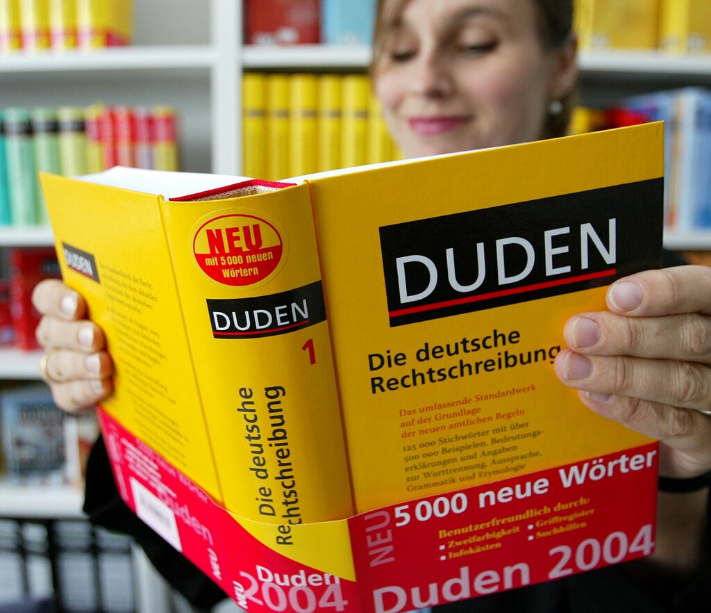 Auberle of Duden editorial poses with the latest edition of Germany's leading dictionary Duden in Mannheim. Anette Auberle of Duden editorial poses with the latest edition of Germany's leading dictionary Duden in Mannheim August 25, 2004. Two of Germany's biggest news publishers earlier this month said they would abandon new spelling rules that millions of schoolchildren have learned since 1998, rekindling a long-running battle over the German language. REUTERS/Alex Grimm - RTR97O7